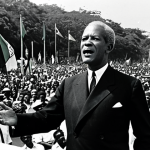 **Image:** Norman Manley delivering a speech at a political rally in Kingston, Jamaica, 1960s. He is wearing a suit and tie, gesturing emphatically. The crowd is diverse and engaged. Background shows Jamaican flags and banners with PNP slogans. "Professional photography, historical accuracy, fully clothed, appropriate attire, safe for work, correct proportions, natural pose, family-friendly".